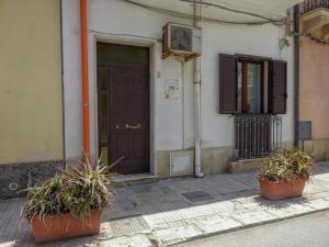 a building with two potted plants in front of a door at Maison Vivian Apartment in Marzamemi