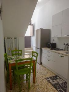 a kitchen with a table and green chairs in a kitchen at Maison Vivian Apartment in Marzamemi +4 photos