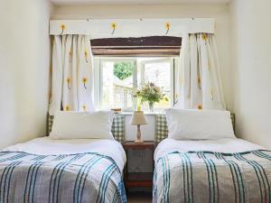 two beds in a room with a window at Trevadlock Manor by Smart Welcomes in Launceston