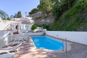 a swimming pool with lounge chairs next to a house at Casa Trino in Almuñécar