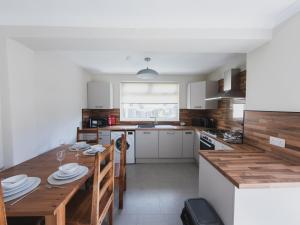 a kitchen with a wooden table and a dining room at The Cosy Plover in Johnstone