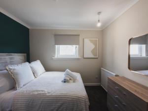 a bedroom with a bed with a teddy bear on it at The Cosy Plover in Johnstone