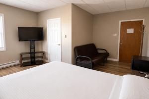a bedroom with a bed and a chair and a television at Hotel Blanc-Sablon in Blanc-Sablon