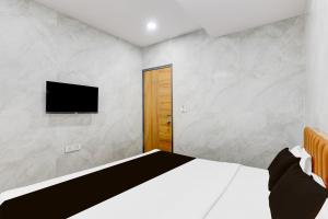 a bedroom with a bed and a flat screen tv at Hotel O Lotus in Surat