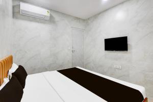 a bedroom with a bed and a flat screen tv at Hotel O Lotus in Surat