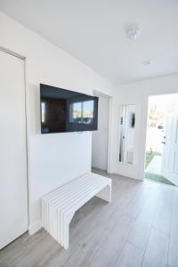 a white living room with a bench and a tv at Waterfront Cabana 2 Key Largo in Key Largo