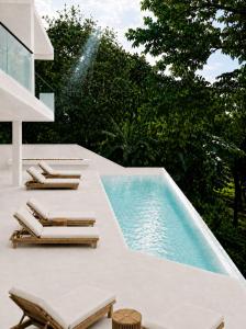 a swimming pool with lounge chairs next to a swimming pool at Maxx Una in Unawatuna
