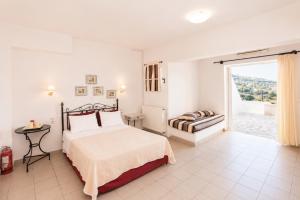 a white bedroom with a bed and a window at 9 Muses in Andros