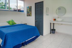 a bedroom with a blue bed and a sink at Charlys Room 9 in San Salvador