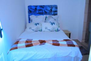 a white bed with a plaid blanket on it at inspan lodge in Bellville South