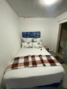 a bedroom with a bed with a plaid blanket on it at inspan lodge in Bellville South