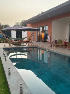 a swimming pool with chairs and an umbrella next to a house at Ker Ar Mor - Villa 3 chambres avec piscine privée à Nguerigne in Sintiân