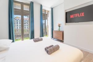 a white bedroom with a large bed and a tv at Maison Rouget - Chambre 1 - Mimosa in Nice