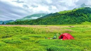 a tent in a field with mountains in the background at Magic Valley Devroopa Trek - Pickup and drop to New Delhi in Kulu