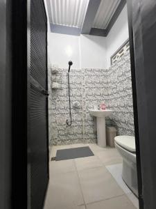 a bathroom with a shower and a toilet and a sink at Tiya Cheding Boarding House in Carolina