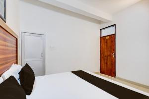 a bedroom with a white bed and a wooden door at Hotel O Royal in Rewāri +21 photos