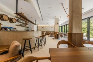 a restaurant with wooden tables and chairs and windows at Odat n'Bogë - Breakfast Included by PikHost in Bogë