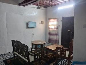 a room with a table and chairs and a tv at Beiytul Noor Apartment in Lamu