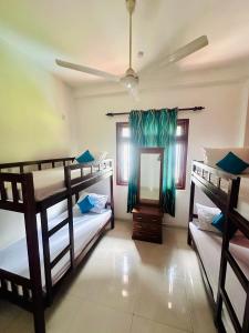 a room with three bunk beds and a mirror at Panda House in Galle +6 photos