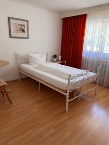 a white bed in a room with a red curtain at Hotel-Restaurant Maien in Todtmoos