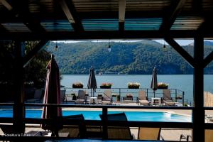a view of a swimming pool with chairs and umbrellas at Pensiunea Celestin in Eşelniţa