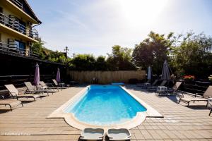 a swimming pool with chaise lounges and chairs at Pensiunea Celestin in Eşelniţa