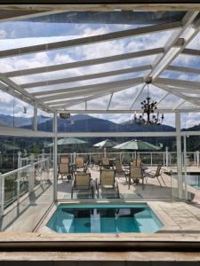 a patio with a pool and chairs and a view of the mountains at Pousada Terraço Penedo in Penedo