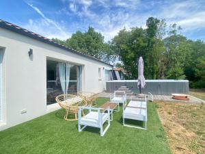 a patio with chairs and a table and an umbrella at La Maison Moderne - 6 pers - SPA - Piscine in Saint-Sauveur-dʼAunis