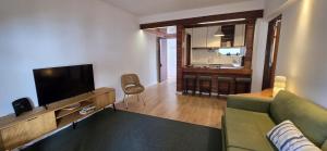 a living room with a green couch and a flat screen tv at At the beach with a private garden in Carcavelos