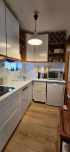 a kitchen with white cabinets and white appliances at At the beach with a private garden in Carcavelos