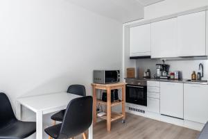 a kitchen with white cabinets and a table and chairs at Modern Studio in Downtown Lahti in Lahti +8 photos