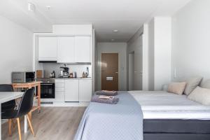 a bedroom with a large bed and a kitchen at Modern Studio in Downtown Lahti in Lahti