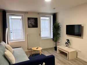 a living room with a blue couch and a tv at Studio cosy au vieux centre in Cormeilles-en-Parisis