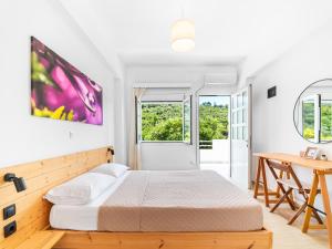 a bedroom with a bed and a desk and windows at Bodini's Rooms in Himare