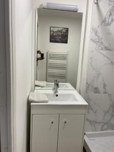 a white bathroom with a sink and a mirror at Studio cosy au vieux centre in Cormeilles-en-Parisis
