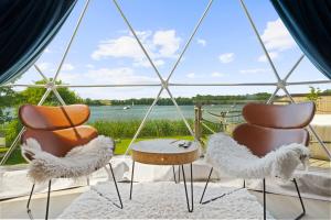 two chairs and a table with a view of the water at Lake Glamp Mikołajki - Adults Only in Mikołajki