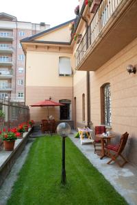 un patio con césped con mesas y sillas en B&B Casa Liberty en Acqui Terme
