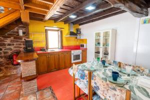 a kitchen with a dining table and a kitchen with yellow tiles at El Llagar de Ternín in Villaviciosa