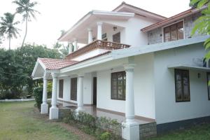 a house with white walls and columns at VJ Riverfront Villa in Champakulam