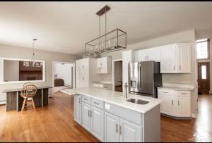 a large kitchen with white cabinets and a refrigerator at AEQ Luxury House 1 in Orland Park