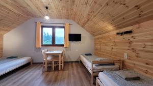 a room with two beds and a table and a window at Wrzosowe Wzgórze Domki 3 sypialnie in Chęciny