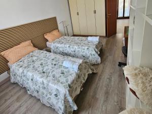 two beds in a room with wooden floors at La dimora di Gabi in Marghera