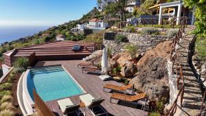 a house with a swimming pool on a hill with chairs at Massapez Royals in Fajã da Ovelha