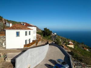 a white house with a car parked on a hill at Massapez Royals in Fajã da Ovelha +47 photos