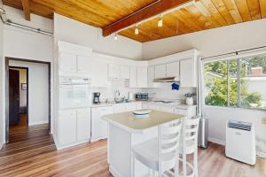 a kitchen with white cabinets and a wooden ceiling at Rockaway Beach View in Port Blakely