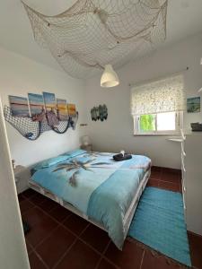 a bedroom with a bed with blue sheets and a window at Fonte da Telha Beach Hostel in Costa da Caparica