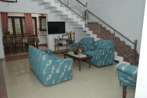a living room with two blue chairs and a staircase at VJ Riverfront Villa in Champakulam