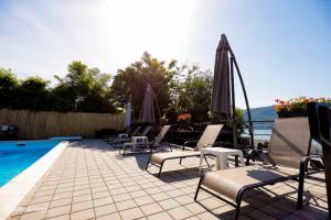 a group of chairs and umbrellas next to a swimming pool at Pensiunea Celestin in Eşelniţa