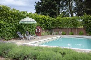 a swimming pool with an umbrella and chairs and a table and an umbrella at 3 Bed in Ringsfield oc-m33329 in Wingfield