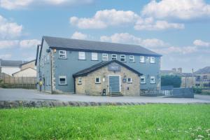 a large blue building with a grass field in front at Bronte Breaks in Haworth